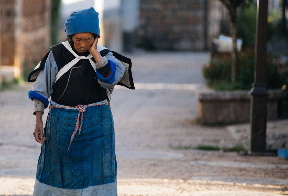  Naxi woman walks to work with an empty basket on her back. 