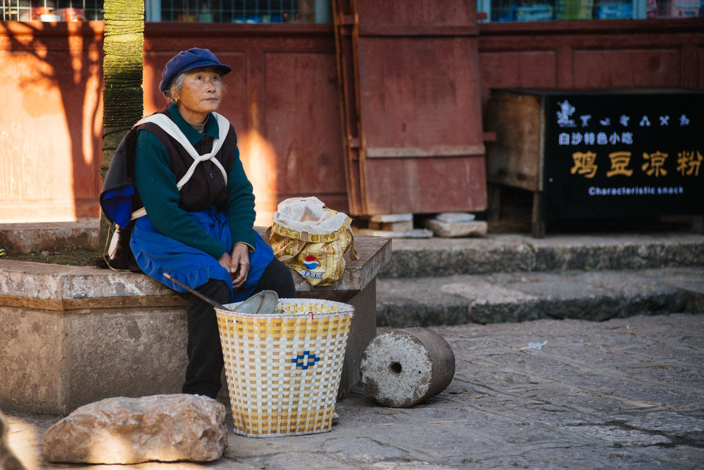  Woman waits for customers to sell fruit from her basket. 