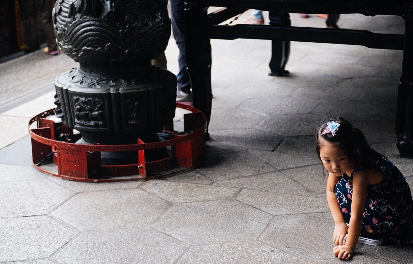 Little girl picks up jiaobei #筊杯, wooden divination pieces of wood that answer yes or no questions. The pieces have a flat side and a curved side. You ask a question and throw them on the floor, if one lands flat and the other curved, that’s a