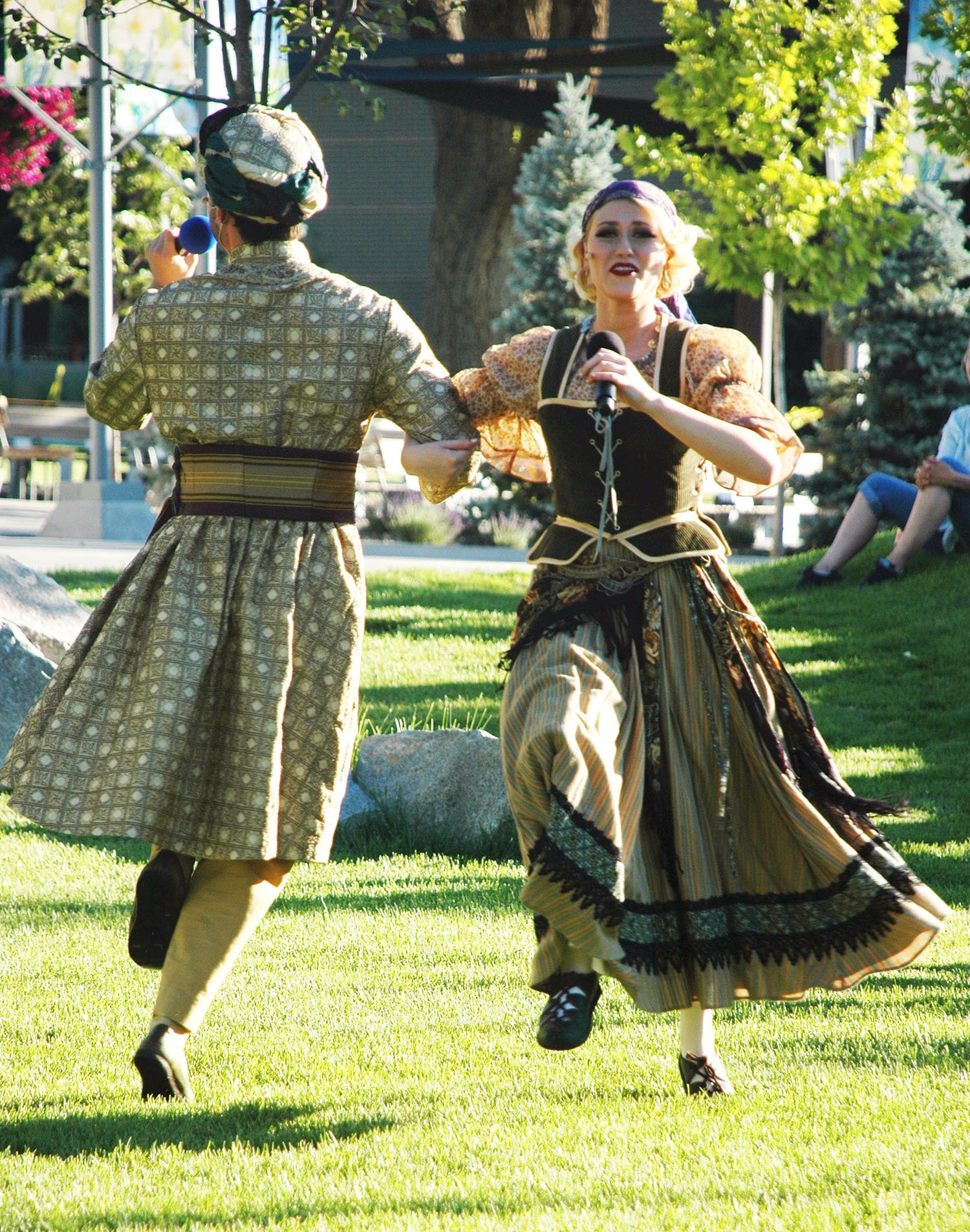 Actors dancing on a lawn during a play rehearsal