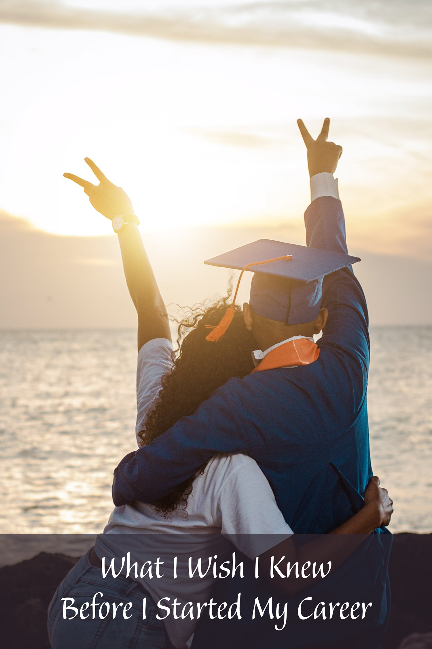 Two people looking at the ocean, one is wearing a blue graduation cap and gown.