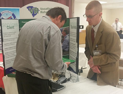Photo: Joseph Anthony, Rehabilitation Technology Engineer, discusses VR services with a guest at the Community Resource Fair in Williamsburg.