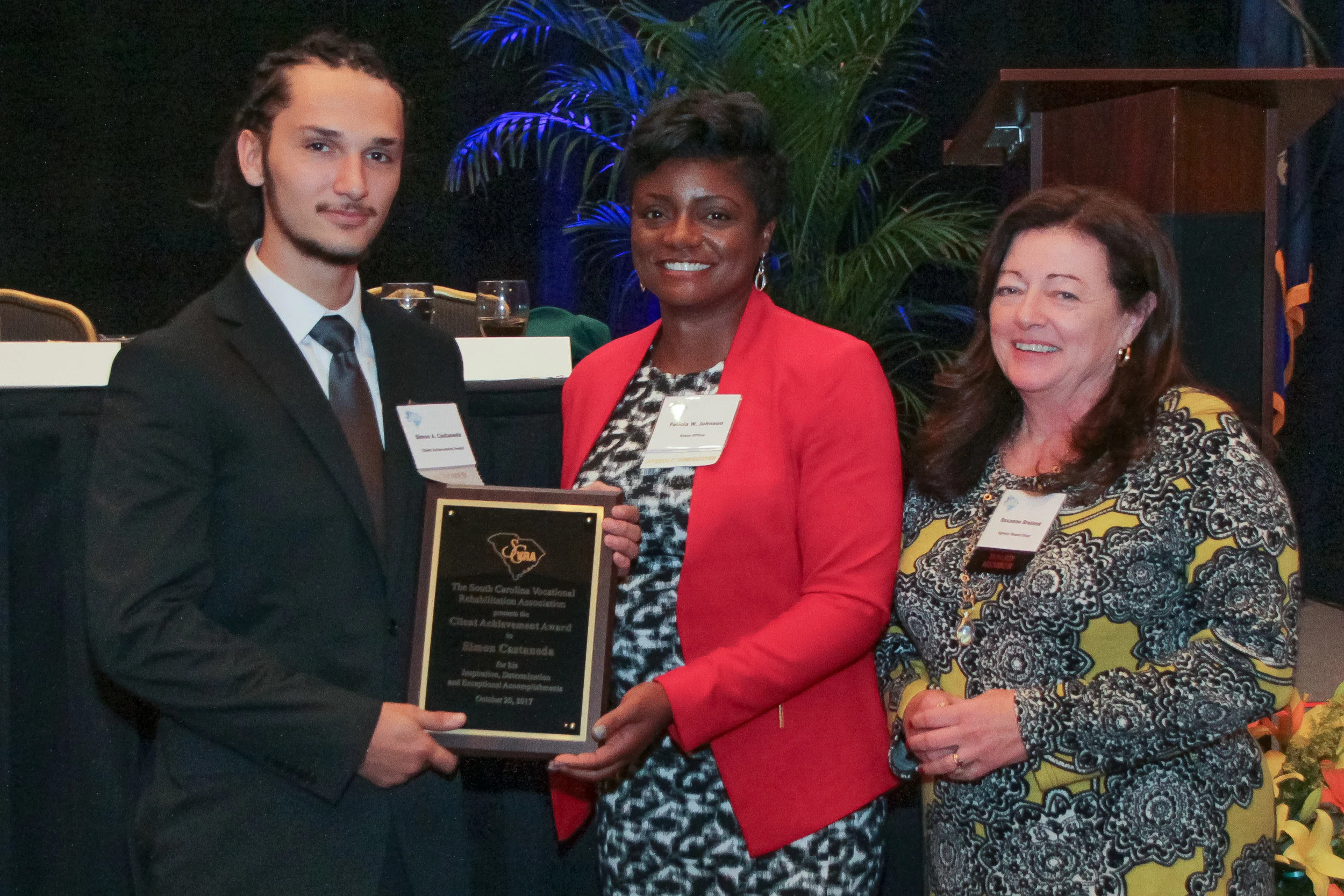 Simon Castaneda (left) receives the 2017 Client Achievement Award from Felicia Johnson, VR Interim Commissioner, and Dr. Roxzanne Breland (right), Chair of the SC State Agency of Vocational Rehabilitation.