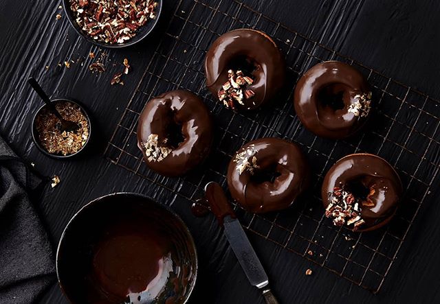 Chocolate glazed donuts with pecans &amp; gold flecks on black. #props #propstylist #propstyling #prophouse #propcloset #propcollection #prop #foodphotography #foodphotographyprops #lovemyjob #hoarder #create #foodporn #instafood #instagood #producti