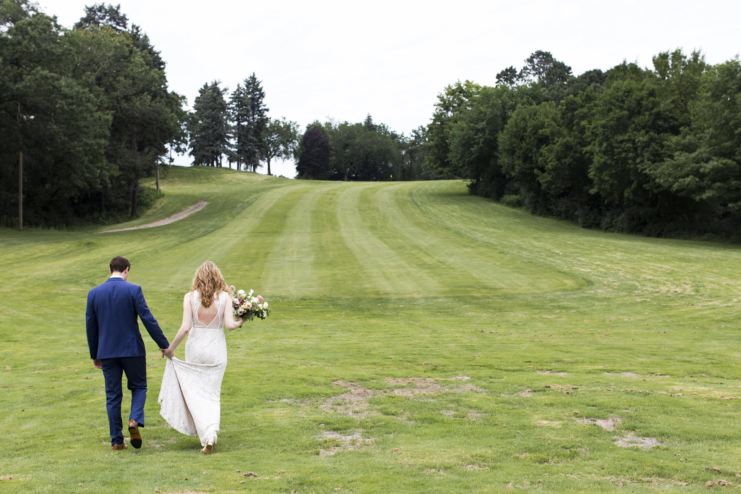 Nick holds Robin’s hand as they walk out into a fairway for photos at Theodore Wirth . Wedding by: Jess Ekstrand