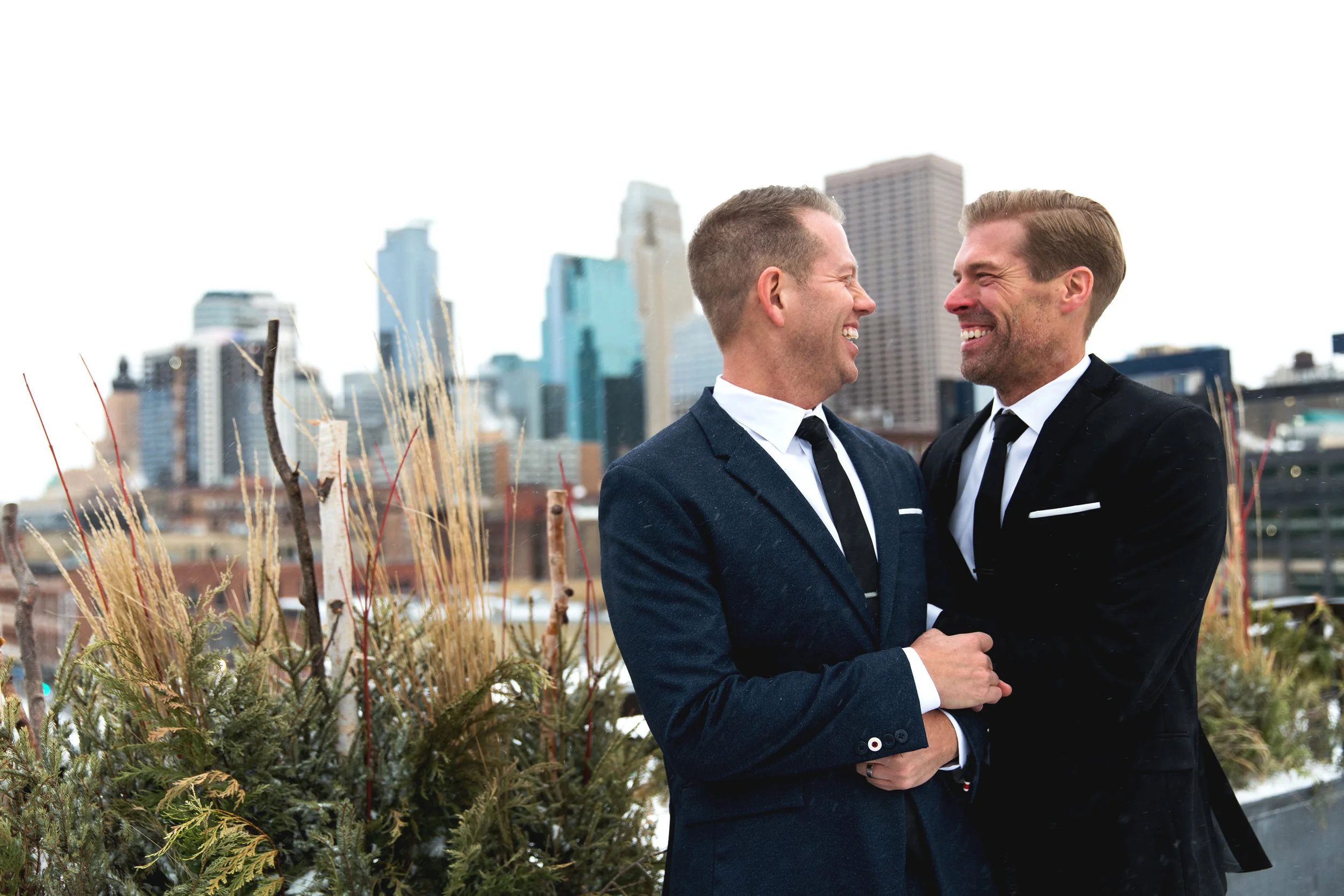 Todd and Jesse stand on the Hewing Hotel rooftop for photos with the Minneapolis skyline in the background. Wedding by: Nicole McCoy