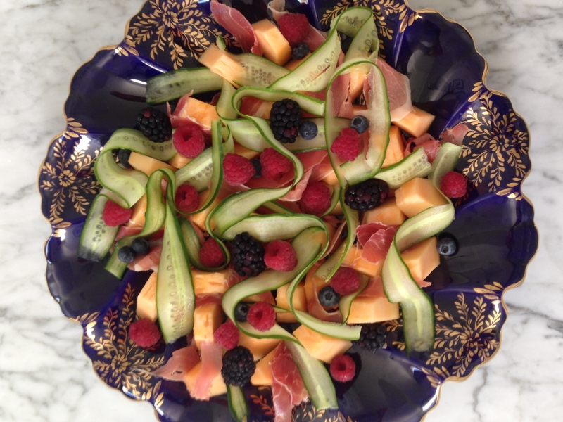 Antepasto de presunto cru com melão orange, fitas de pepino e frutas vermelhas.