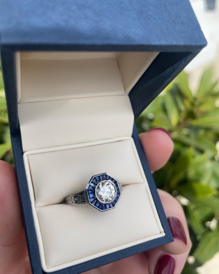 The most delightful Scottish themed blue jewel for a very lucky lady on her birthday.  We have engraved a thistle motif on the heavy, tapered band, custom cut an octagonal, finer grade blue sapphire surround and an immaculately set diamond centre in 