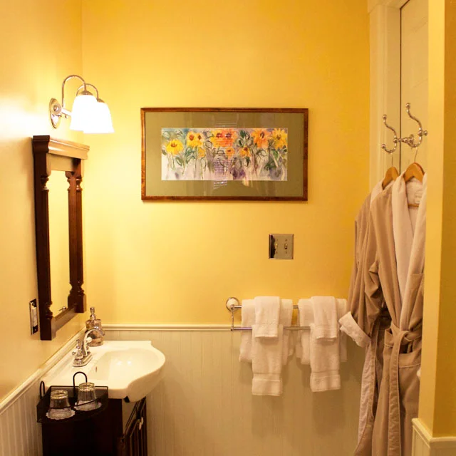 Bathroom of the conservatory room featuring plush bathrobes, porcelain sink, and shower.
