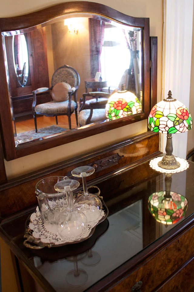 Antique dresser with mirror presents wine glasses to enjoy while at Burlington’s Willard Street Inn.