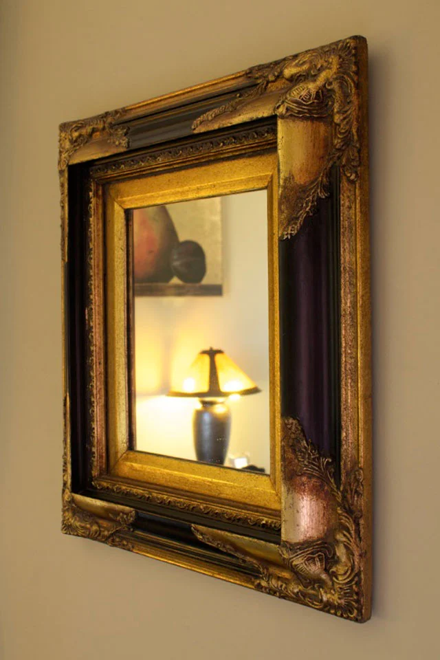 Antique black and gold mirror hung on the wall in Cobblestone Room At Willard St. Inn.