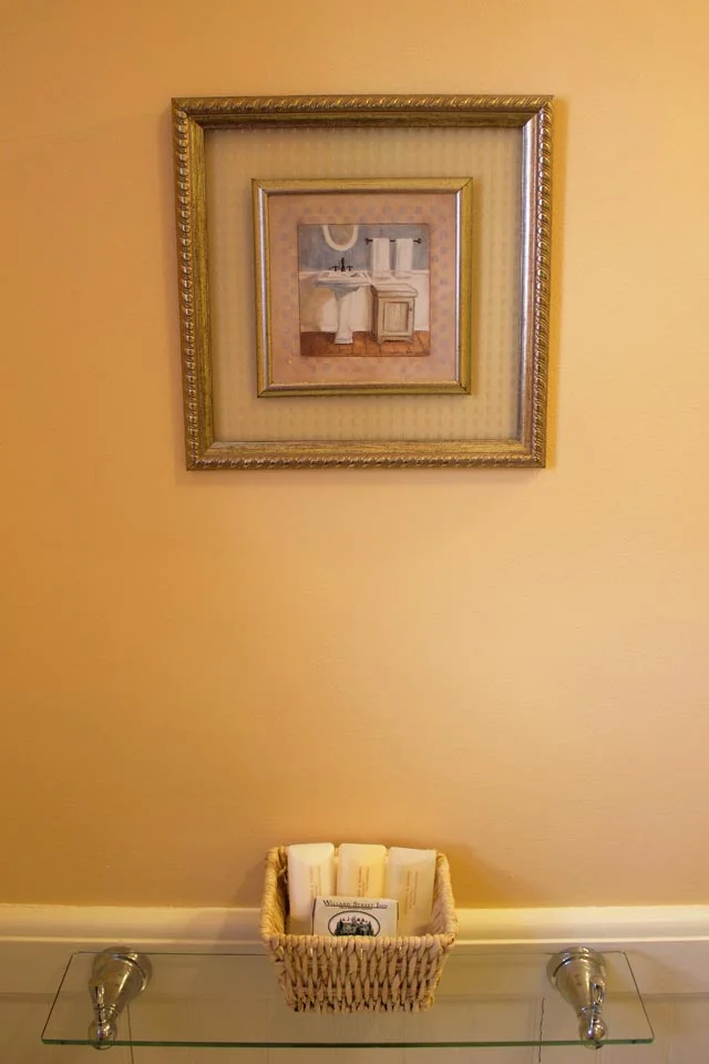 Glass shelf displaying luxurious amenities in the bath of Cobblestone- Rm 6.