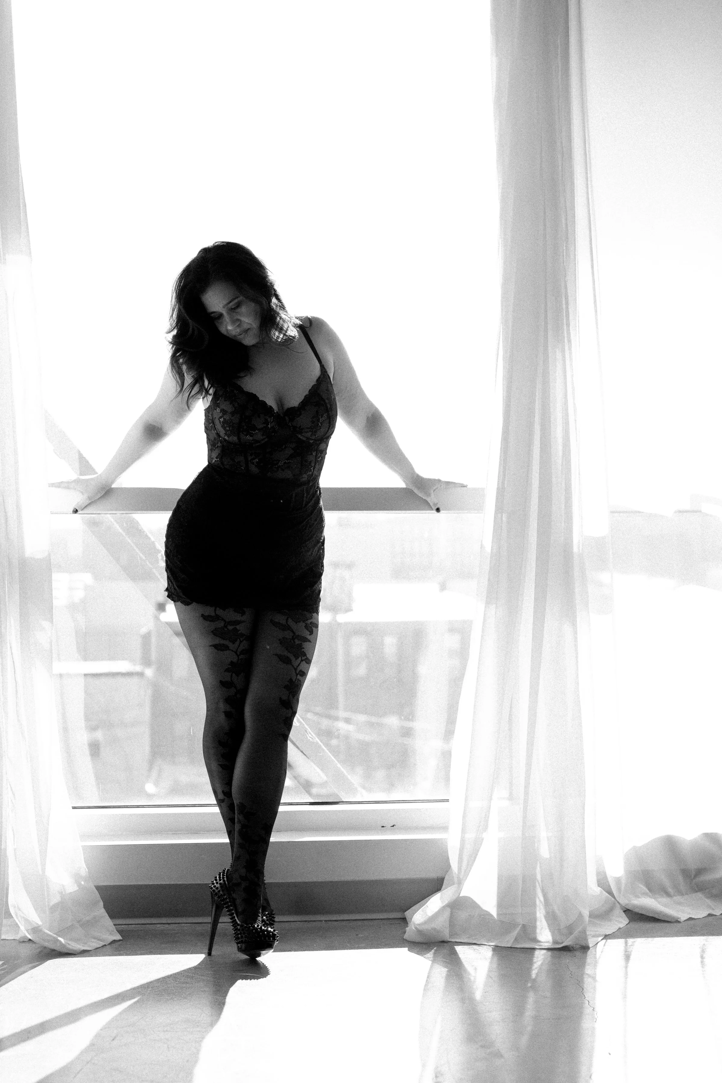 Woman in tight lacy dress standing at windows