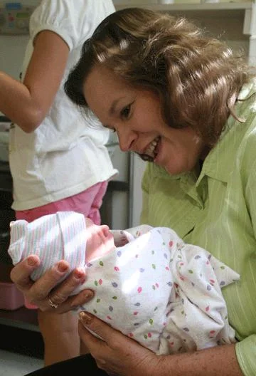 Photo of Mike's wife holding their newborn granddaughter at the hospital.