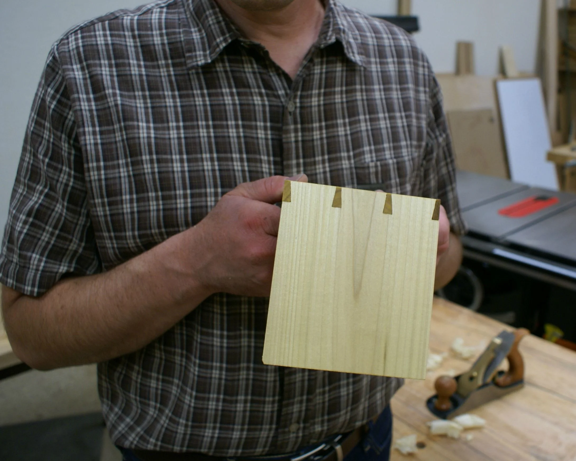 A student with their first dovetail joint. This joint is made primarily with a specialized saw called a dovetail saw. It consists of two pieces of wood, a tail board and a pin board, joined together.
