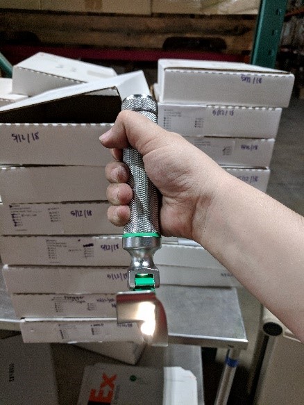 A fully assembled laryngoscope and piles of complete laryngoscope kits packed by HOMES students.