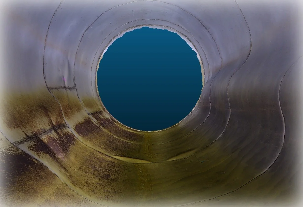 Looking up inside a large, cylindrical pipe with a circular opening at the top, showing the water below.