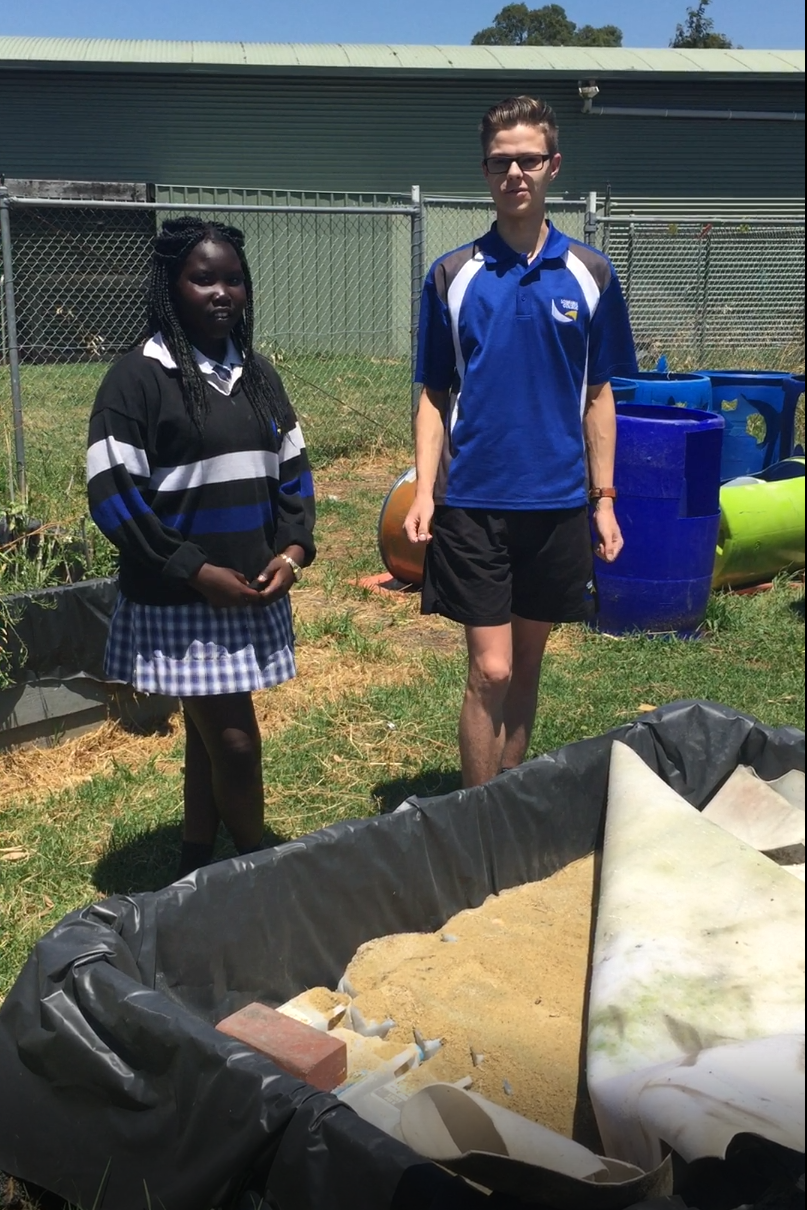 Nyachou Gawar and Trent Euman in front of a Wicking Garden under construction