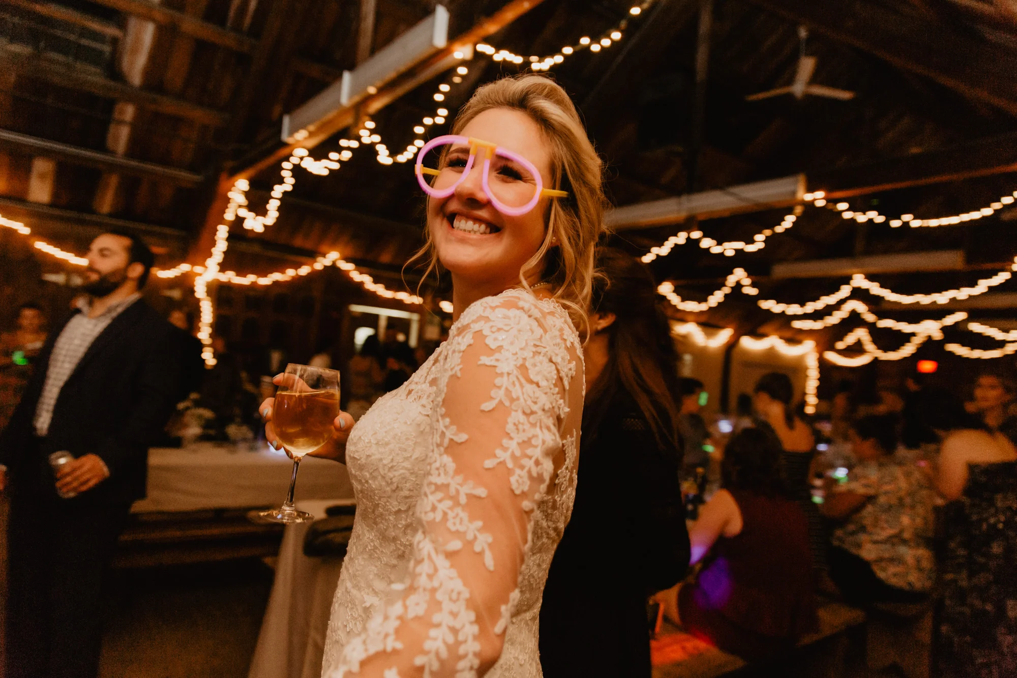 The bride poses while wearing a pair of glow stick sunglasses