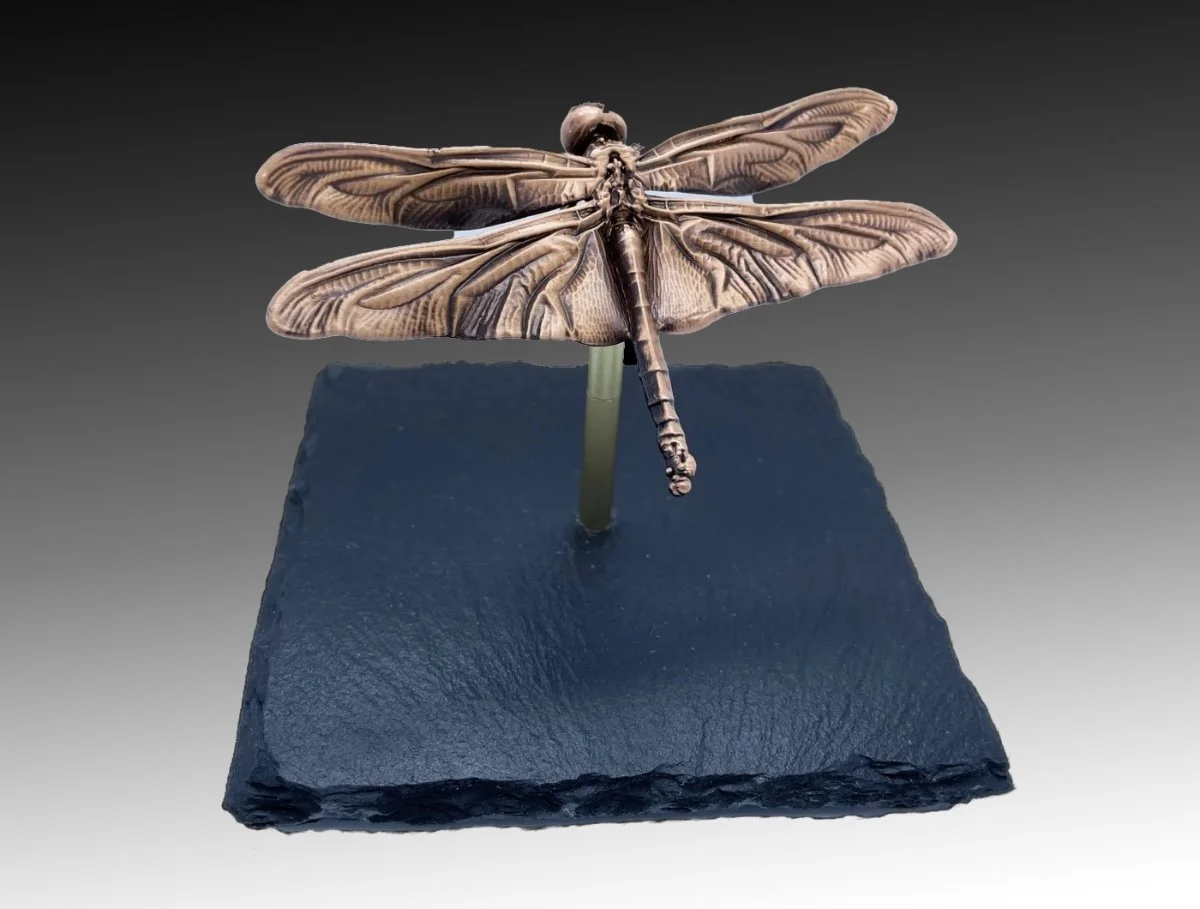 Detailed model of a dragonfly sculpture on a pedestal.