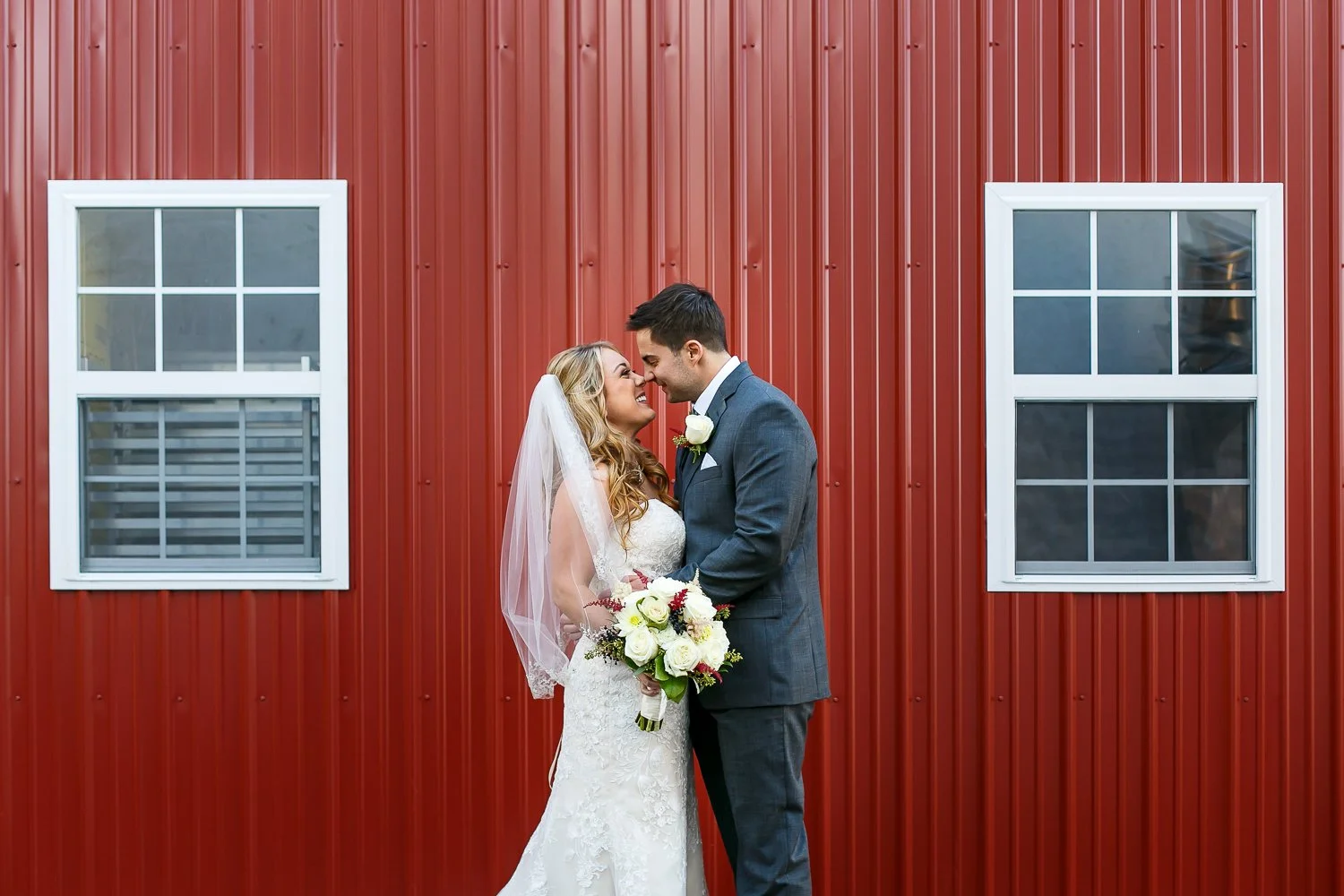 WED-Highlights-015-bride-and-groom-cuddle-up-in-front-of-rustic-barn-on-wedding-day.JPG