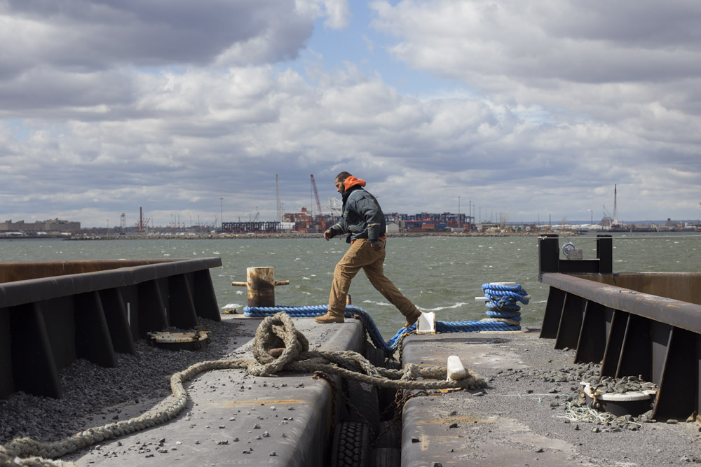  Walter Serrano, a tugboat deckhand for Brown and Sons towing, crosses between barges while moving cargo in a small inlet by Red Hook.&nbsp; 