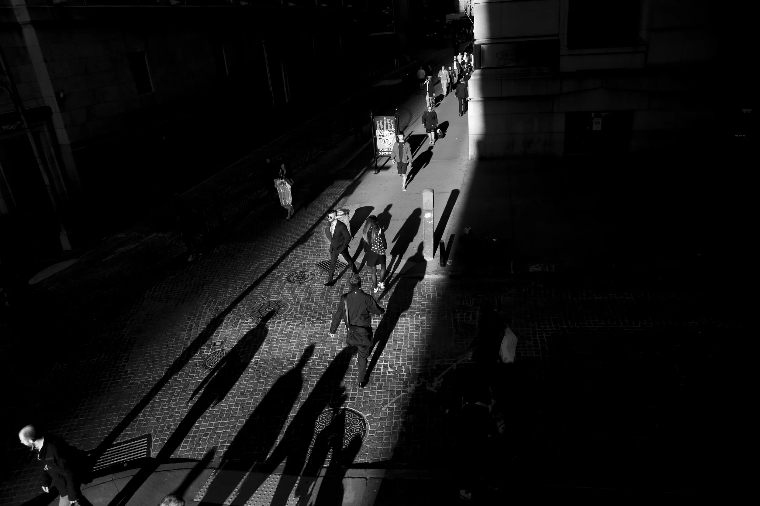 Traders cross a shaft of light in the early hours of the morning on the corner of Wall Street near the New York Stock Exchange.