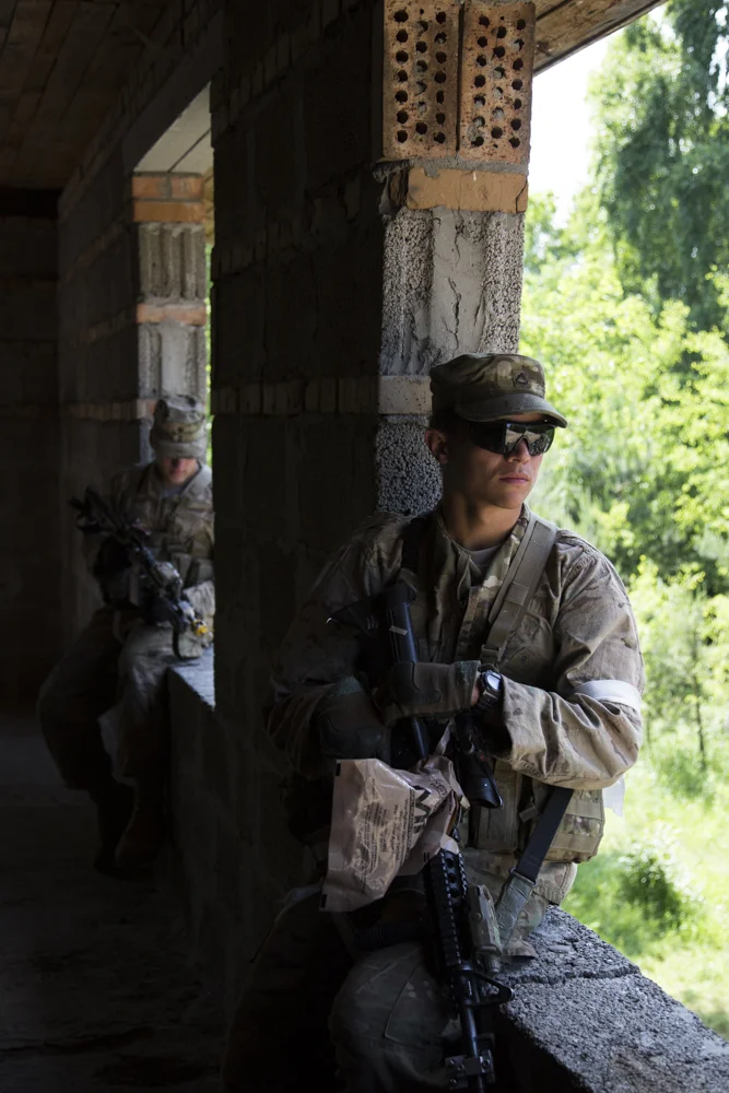 A soldier in the U.S. Army 173rd Airborne waits for a training exercise to begin. He's taped an MRE bag over the ejection port of his rifle, as command wanted all soldiers to collect the blank shell casings they fired during the exercise. 