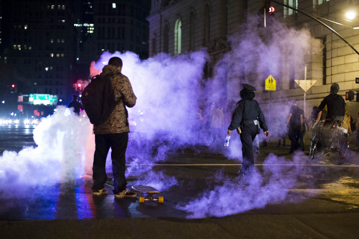 A protestor checks his phone next to steaming manhole covers in lower Manhattan on the first night of protests against a Missouri grand jury's decision not to indict the police officer who shot Mike Brown, an unarmed 18-year-old in Ferguson, Missouri. November 2014. 