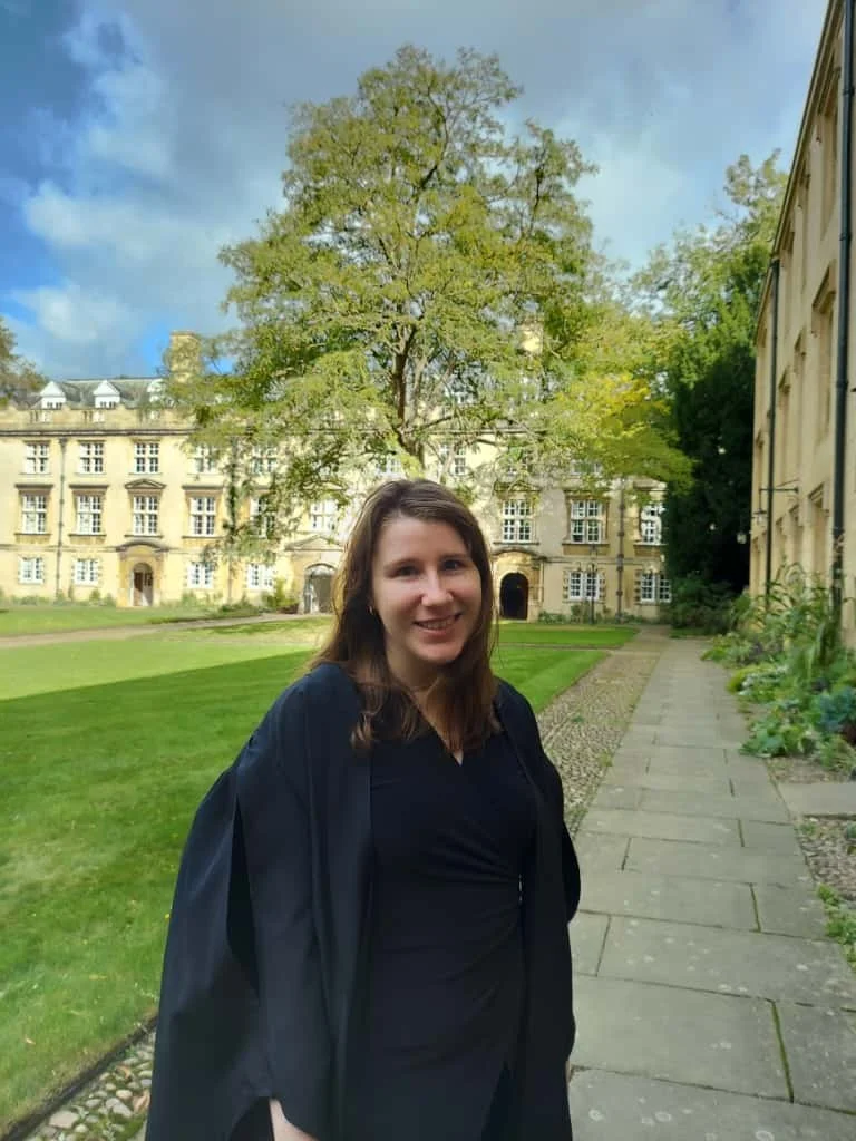 President Sarah hinkel, standing in front of a tree in christ’s college wearing a black gown