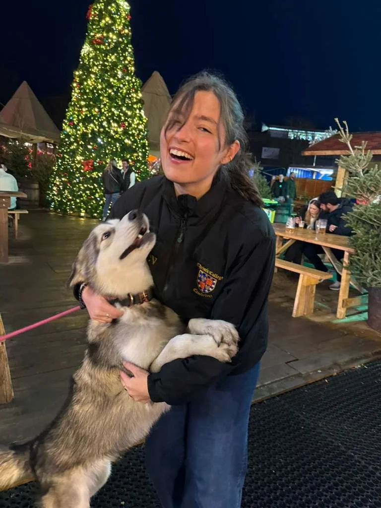Alex is holding a dog at a Christmas market