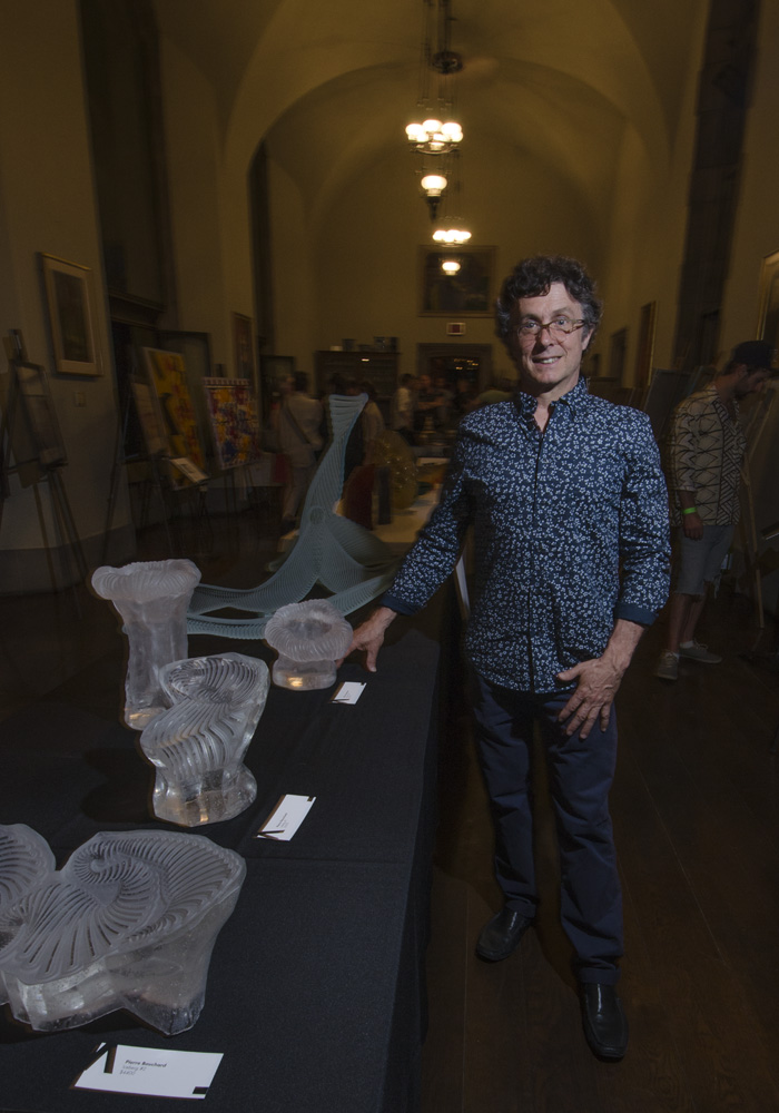 Pierre Bouchard standing with some of his glass sculptures