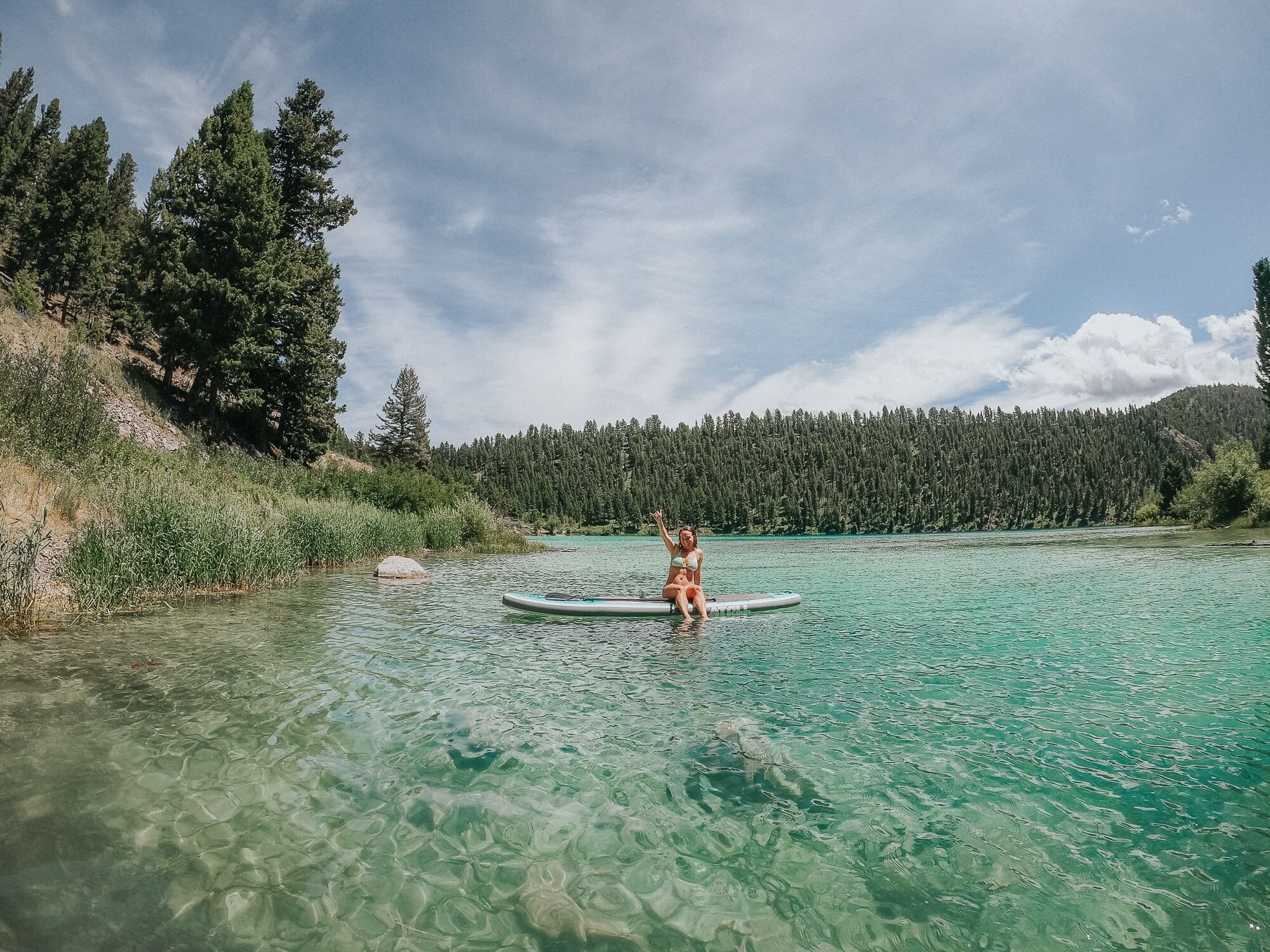 A lady sitting on an Atoll inflatable paddle board