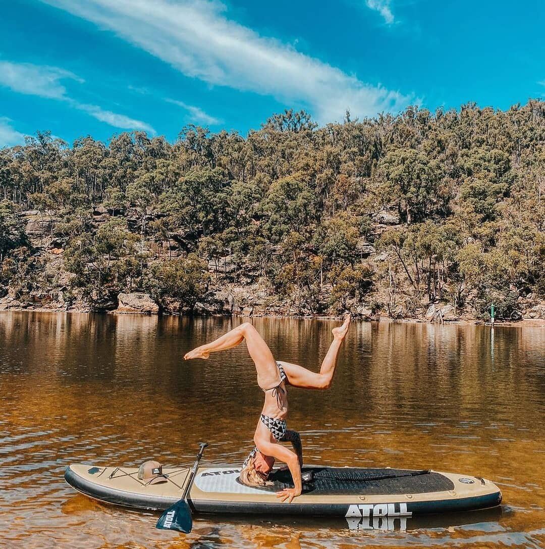 A lady balancing on her head in an inflatable paddle board