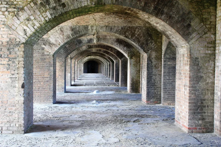 AN INNER CORRIDOR OF FORT JEFFERSON. TO THE LEFT IS THE OUTER COURTYARD. TO THE RIGHT ARE FORTIFIED GUN EMPLACEMENTS. STRAIGHT AHEAD IS OUR ENTERTAINMENT CENTER AND DIRECTLY BEHIND US IS THE SHUFFLEBOARD COURT.
