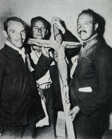 The fellow POWs hold the crucifix carved in honor of Fr. Emil Kapaun. 