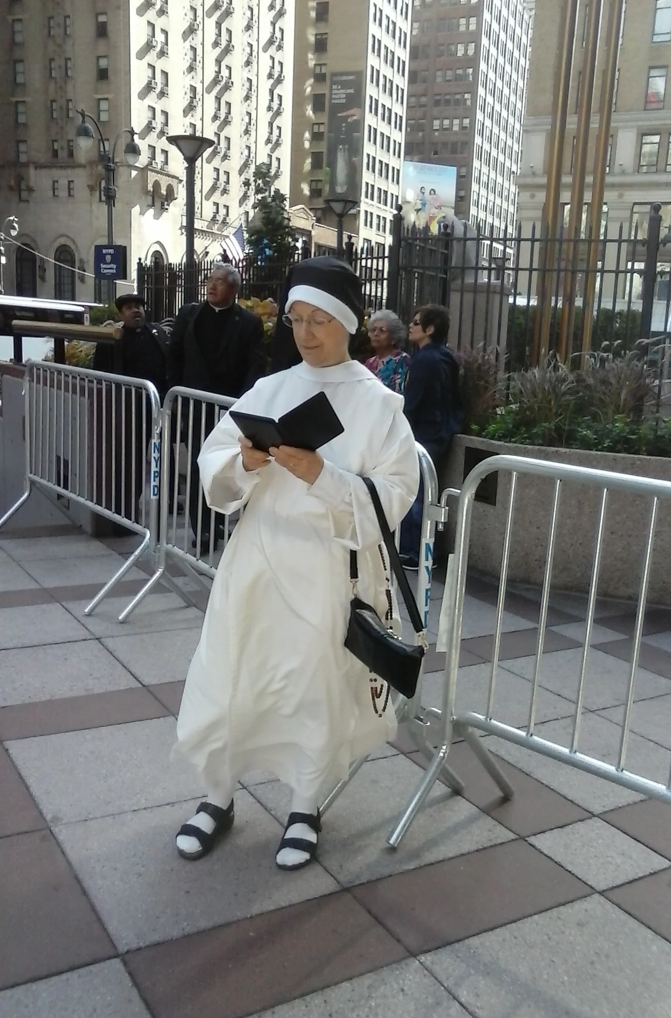 Sr. Denise Marie prays the Divine Office while waiting. Earlier they greeted every Cardinal and Bishop attending who passed them going by the barriers behind Sister!