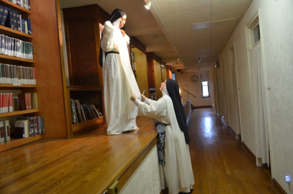 Sr. Mary Catharine measures Sr. Mary Jacinta's habit on the "ramp" in the dormitory.Below this level is the side aisle of the outside chapel of the monastery.