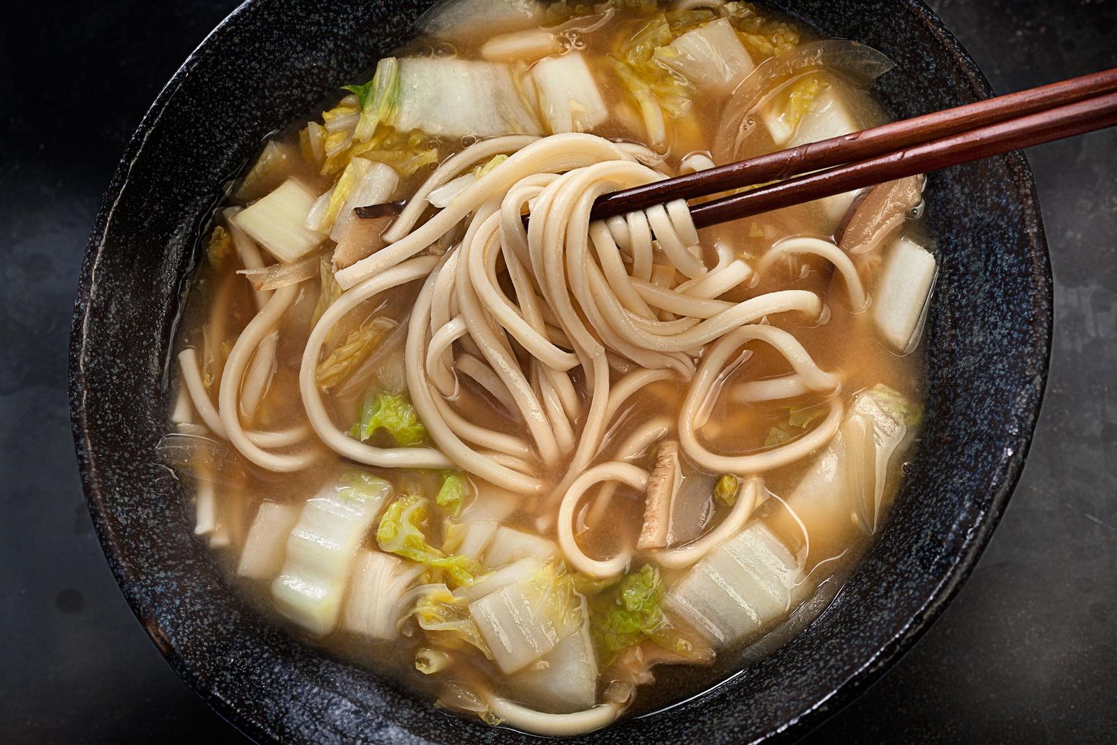 Miso Soup with Napa Cabbage and Udon By Chowhound Ingredients 1 cup sliced dried shiitake mushrooms (about 1/2 ounce) 2 cups boiling water Kosher salt 1 tablespoon vegetable oil 1/2 medium yellow onion, thinly sliced 1 tablespoon peeled and finely chopped fresh ginger (from about a 2-inch piece) 2 medium garlic cloves, finely chopped 6 cups low-sodium vegetable orchicken broth or stock 2 tablespoons soy sauce 1 (12-ounce) package udon noodles 1/2 medium napa cabbage (about 12 ounces), cored, halved lengthwise, and cut crosswise into 1-inch pieces 1/2 cup white miso 4 large eggs (optional) Instructions 1Place the mushrooms in a medium heatproof bowl and add the boiling water. Let sit until the mushrooms have softened, about 12 minutes. 2Bring a large pot of heavily salted water to a boil over medium-high heat. Meanwhile, heat the oil in a large saucepan over medium heat until shimmering. Add the onion, ginger, and garlic and cook, stirring occasionally, until the onions have softened, about 5 minutes. 3Increase the heat to medium high. Add the broth or stock and soy sauce and stir to combine. Using a slotted spoon, remove the mushrooms from their liquid and add them to the saucepan. 4Measure 1 cup of the mushroom liquid, being careful not to include any sediment from the bottom of the bowl, and add it to the saucepan. Bring to a boil. (Discard the remaining mushroom liquid.) 5Reduce the heat to low and simmer until the mushrooms are tender, about 15 minutes. Meanwhile, add the udon to the pot of boiling water and cook according to the package directions. Drain in a colander and, while stirring, rinse the noodles with cold water until they’re cooled and no longer sticky. Divide all of the udon among 4 deep soup or noodle bowls; set aside. 6When the mushrooms are ready, add the cabbage to the pan, stir to combine, and simmer until the cabbage is tender, about 5 minutes. Add the miso and stir to combine. Taste and season with salt as needed. Crack the eggs, if using, into the simmering mixture and cook until the whites are set and the yolks are still runny, about 2 to 3 minutes. Divide the soup and eggs among the bowls of noodles, being careful not to break the egg yolks. Serve immediately, passing togarashi on the side for sprinkling if so desired.