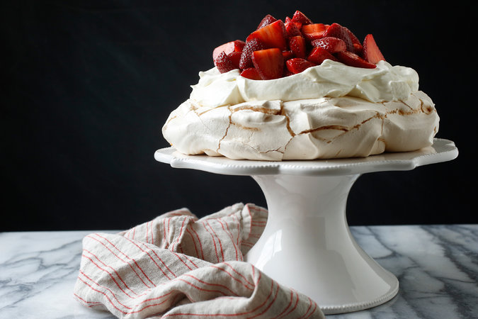 Photo Credit: Craig Lee for The New York Times Strawberry Pavlova NIGELLA LAWSON YIELD 6 servings TIME 2 hours INGREDIENTS FOR THE MERINGUE: 4 egg whites Pinch of salt 1 ¼ cups superfine sugar 2 teaspoons cornstarch 1 teaspoon white-wine vinegar A few drops vanilla extract FOR THE TOPPING: 1 pound strawberries, hulled and halved or quartered ½ teaspoon high-quality vanilla extract 1 teaspoon high-quality balsamic vinegar 2 teaspoons superfine sugar 2 cups heavy cream PREPARATION To prepare meringue: heat oven to 350 degrees. Line a baking sheet with parchment paper, and draw a circle on the paper using an 8- or 9- inch cake pan as a guide. Flip the parchment over so the pencil marking is facing down (this ensures that the pencil won't transfer to the meringue). In bowl of an electric mixer, combine egg whites and salt. Begin beating at low speed, slowly increasing to high. Continue until satiny peaks begin to form; gradually beat in sugar a tablespoon at a time until meringue is stiff and shiny. Sprinkle in cornstarch, white-wine vinegar and vanilla, and fold in gently. Mound onto parchment within circle, and shape into a disk, flattening top and smoothing sides. Place in oven, and immediately reduce heat to 300 degrees. Bake 1 hour 15 minutes. Turn off heat, and allow meringue to cool completely in oven. To prepare topping: in a mixing bowl, combine strawberries, vanilla, balsamic vinegar and sugar. Cover with plastic wrap. Let sit at room temperature at least 15 minutes and up to 2 hours. To serve, carefully peel off parchment and place meringue on a platter or cake stand. Gently crack the top with the back of a soup spoon to make a shallow nest for the whipped cream and berries. Whip cream until it is thick enough to hold peaks, and spoon it evenly over meringue. Cover cream with strawberries, allowing a small amount of their liquid to dribble onto cream. Serve immediately.