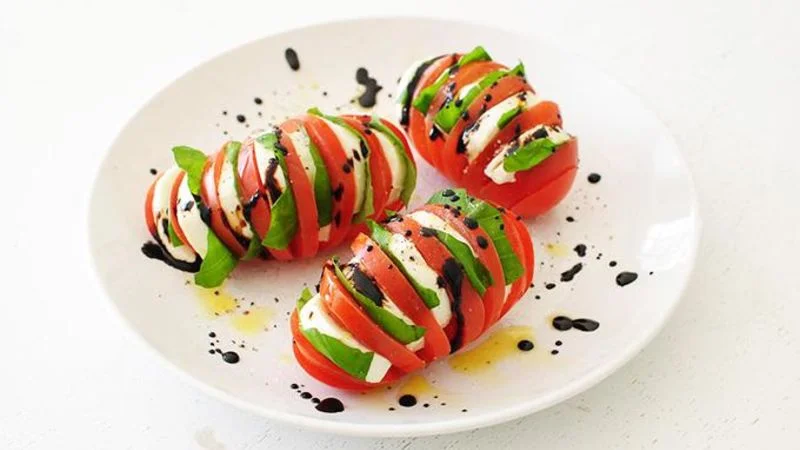 Ingredients 4 Roma tomatoes 1 pre-sliced log fresh mozzarella cheese 10 large basil leaves, torn in half 1/2 cup balsamic vinegar 1 tablespoon extra-virgin olive oil SAVE $ 1 pinch coarse salt and freshly ground pepper Steps Thinly slice each tomato, being careful not to cut through the bottom. Cut each mozzarella slice in half, creating half moons. Layer a piece of basil on top of each mozzarella slice and wedge it between each tomato slice. In the meantime, bring the balsamic vinegar to a boil and cook until thick, 4 minutes. Drizzle the vinegar and oil over the tomatoes and season with a pinch of salt and pepper. Serve immediately.