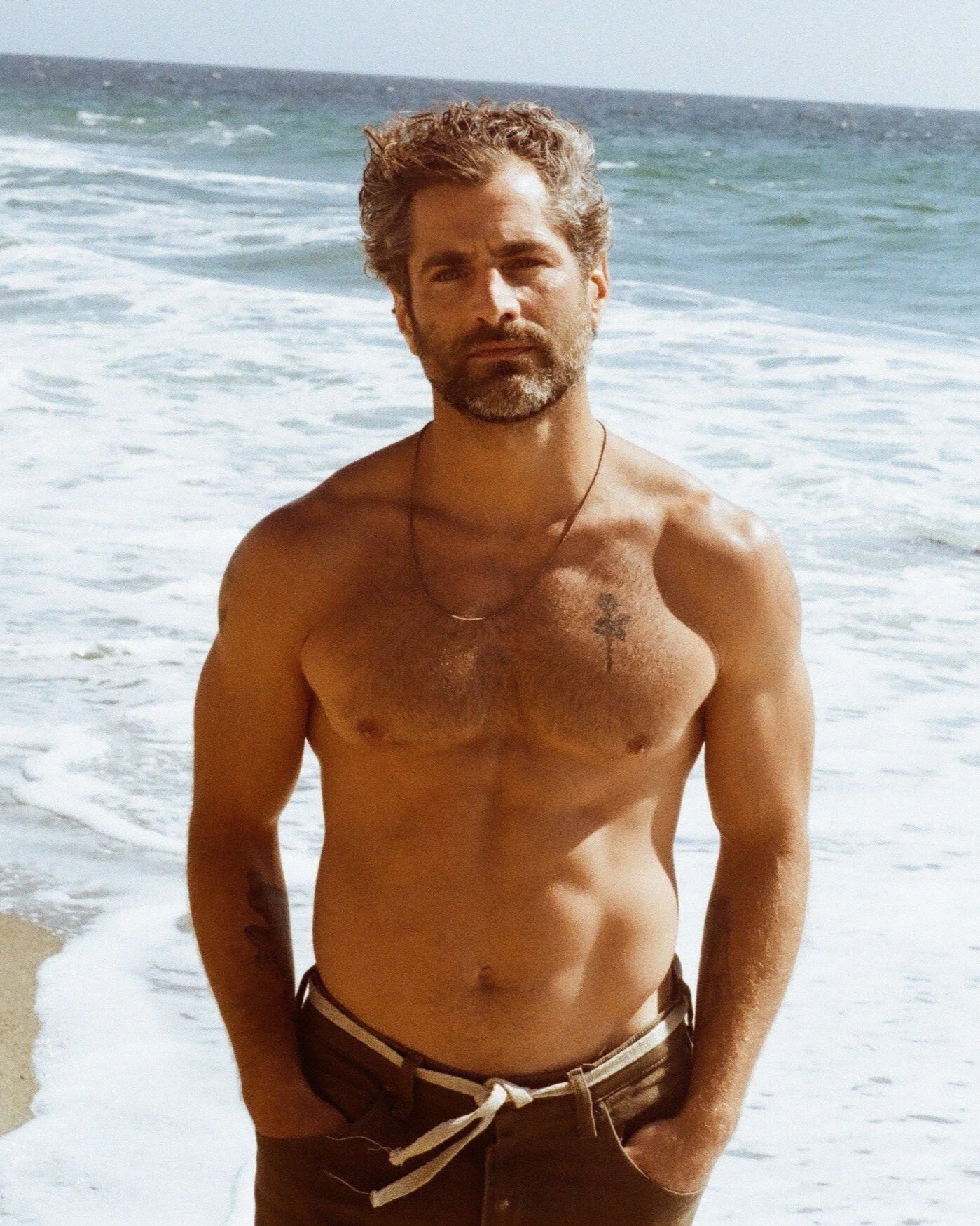 Nick Baga on the beach at the water's edge, looking into the camera