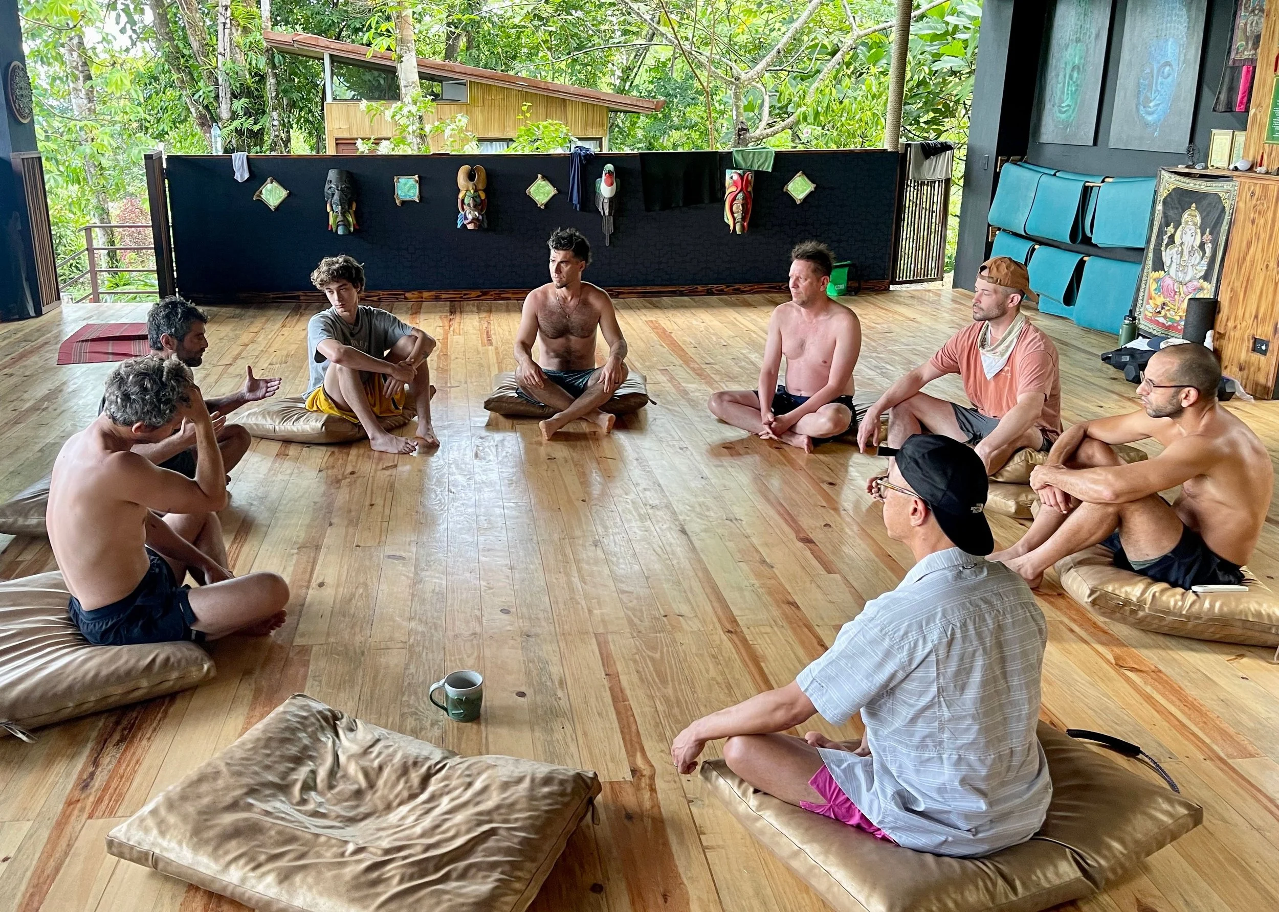 Group of men seated in a circle on a wooden floor during a Lykos retreat