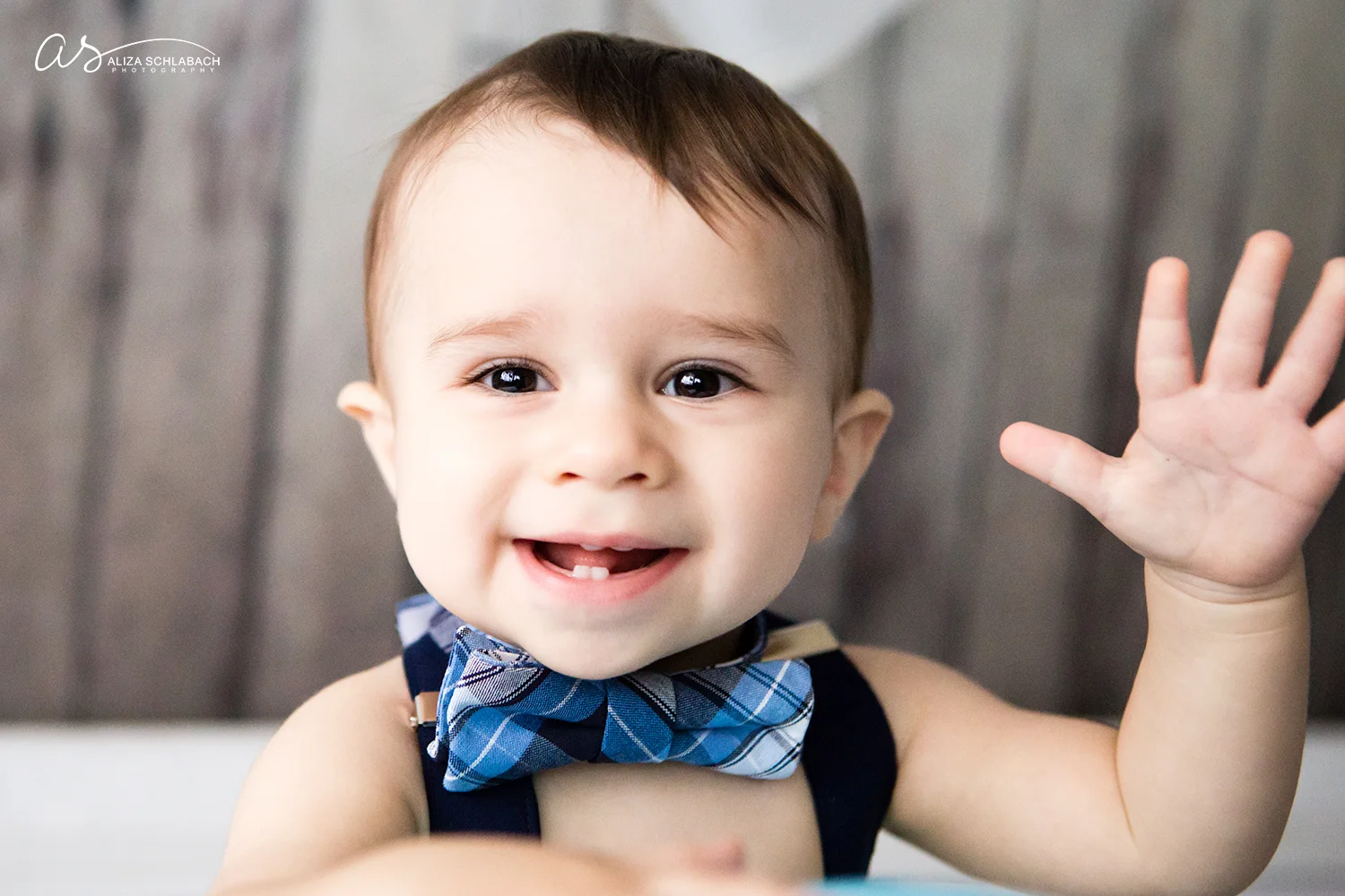 Baby with a bowtie waving at the camera