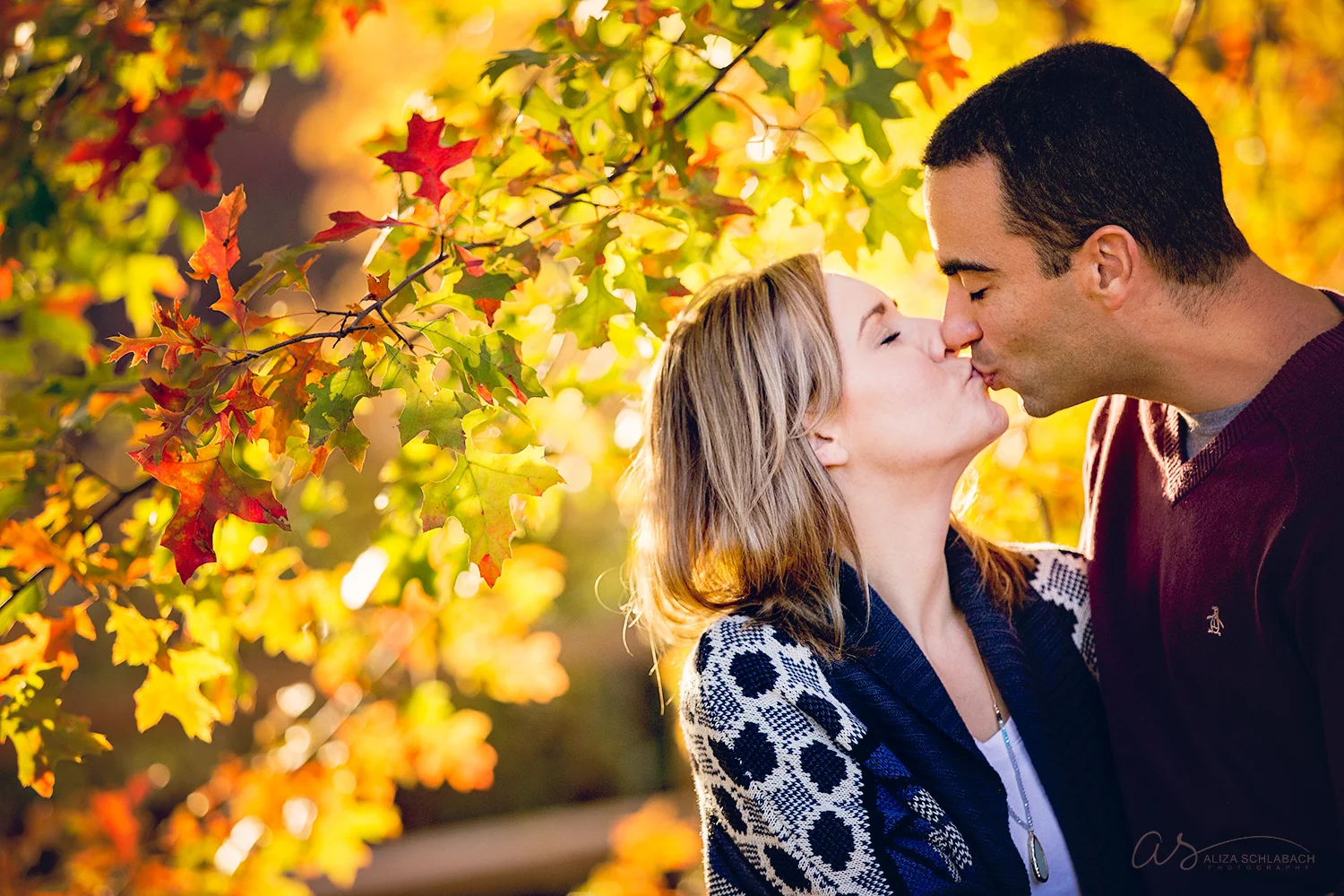 Photo of couple kissing under backlit fall leaves at Haverford College