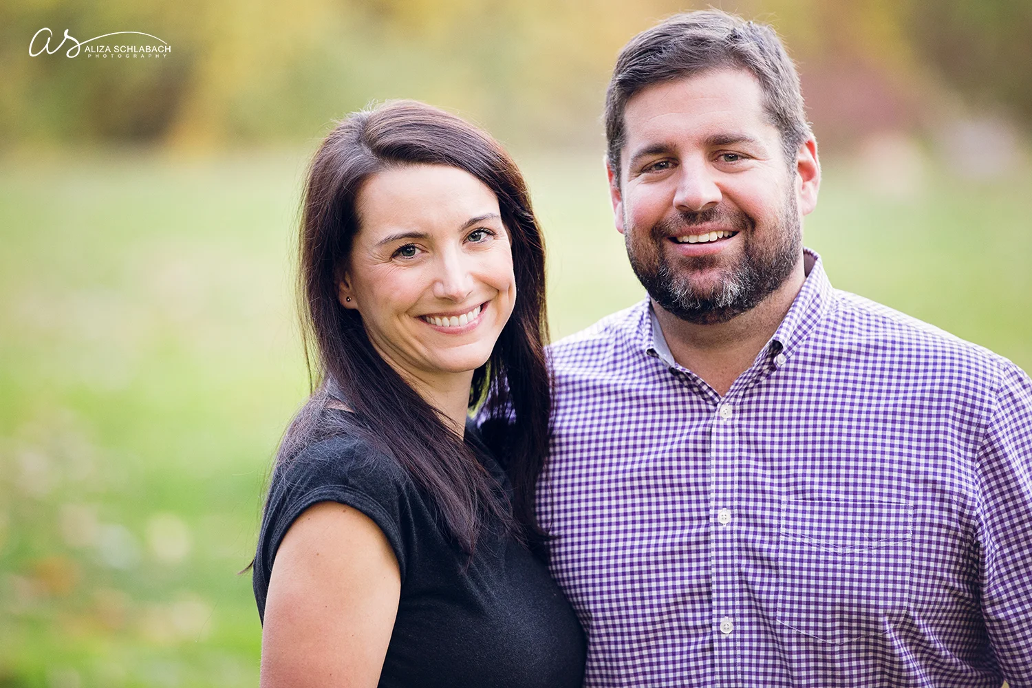Photograph of a couple with grass and trees in the background