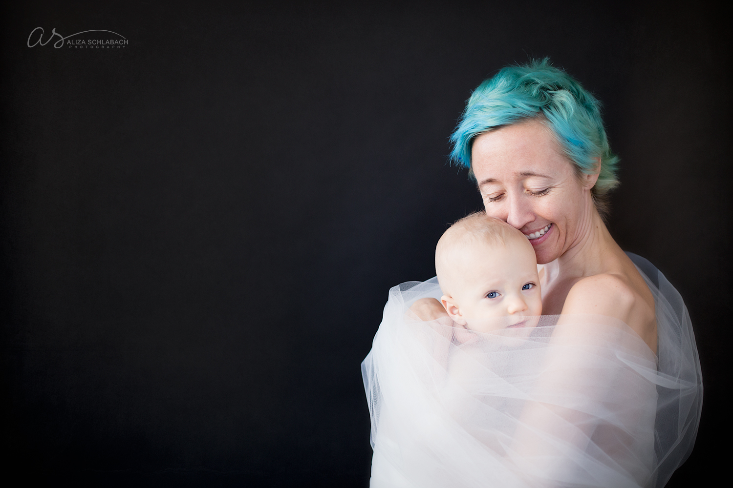 Portrait of a mother with aqua hair holding her baby wrapped in tulle
