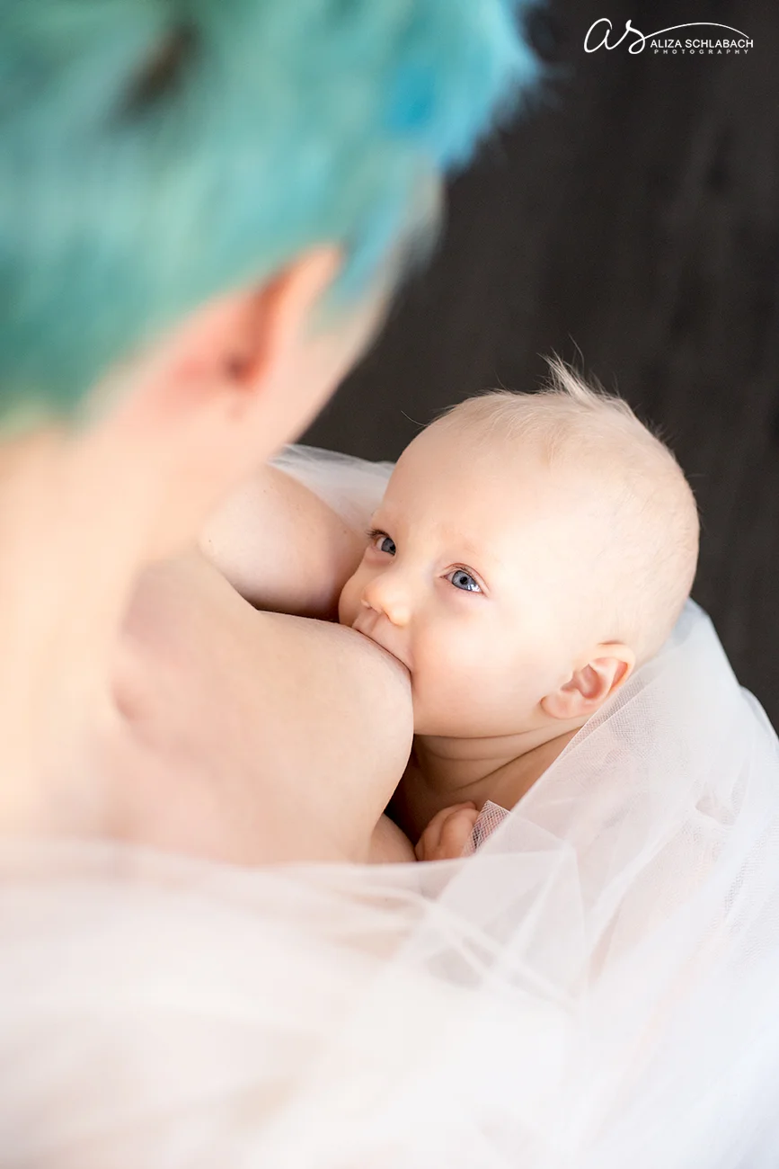 Photo of one year old boy nursing / breastfeeding. Mom has punky aqua hair color.