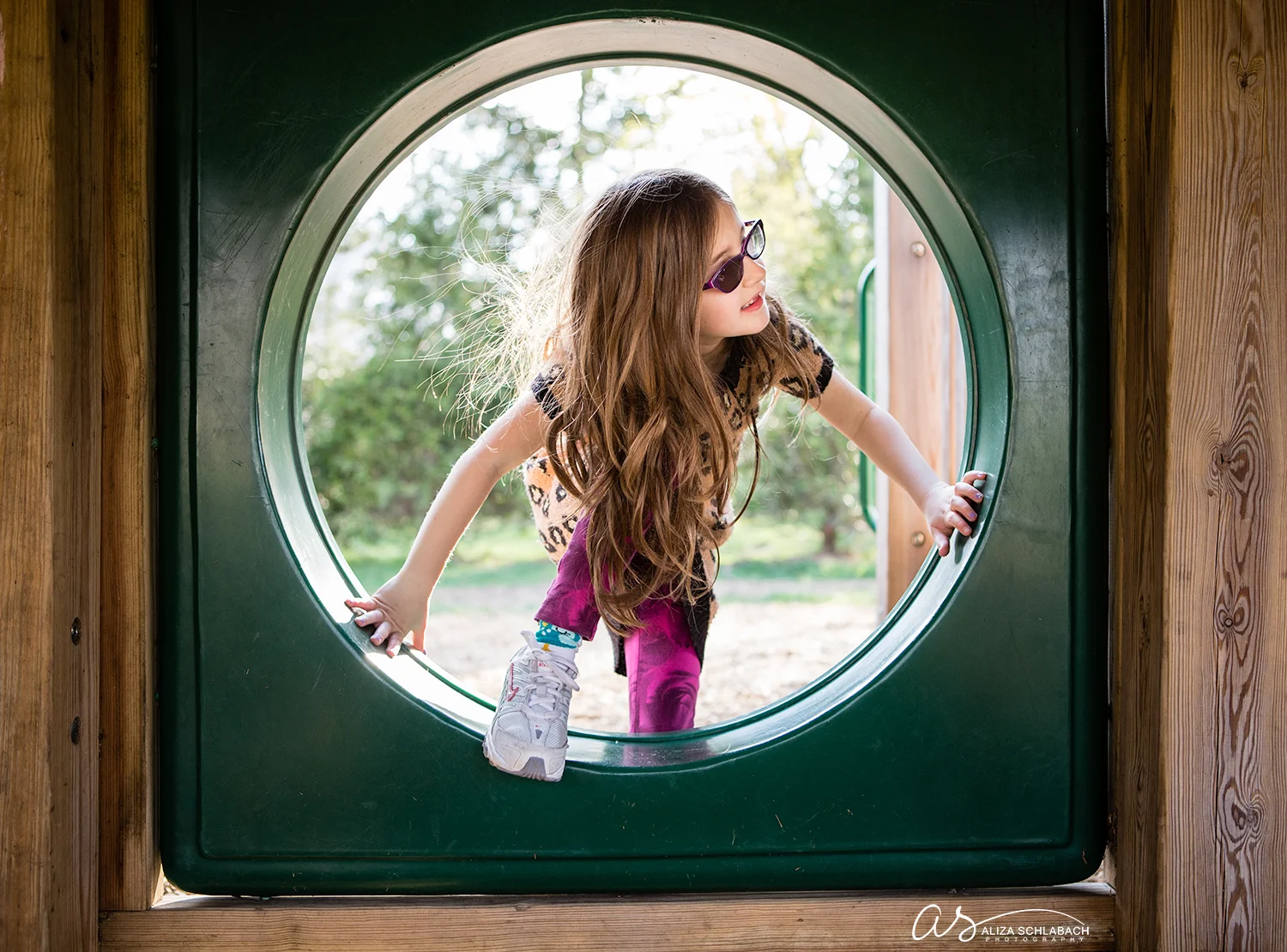 Photo of little girl climbing through playground hole circle