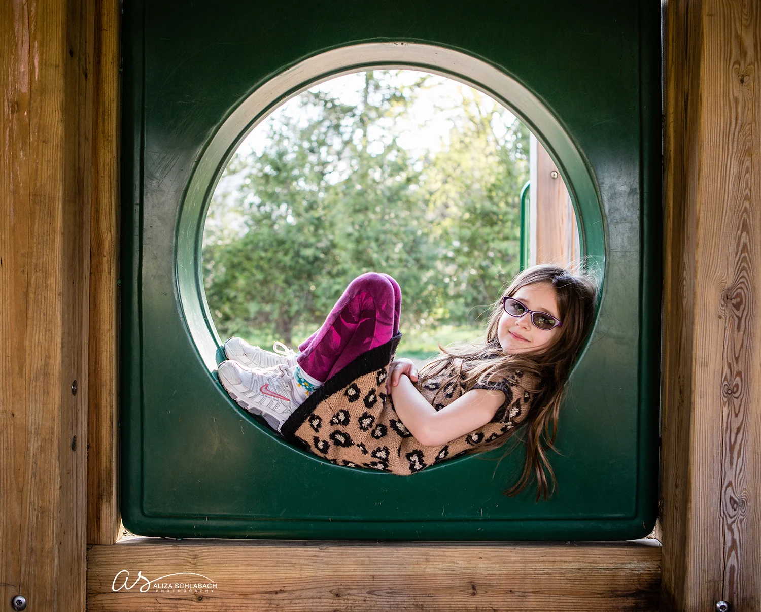 Photo of little girl relaxing in a playground tube